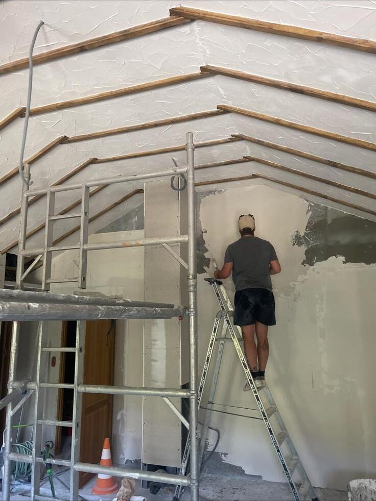 SJM plasterer on scaffold hand-skimming a vaulted internal wall on a Hampshire renovation