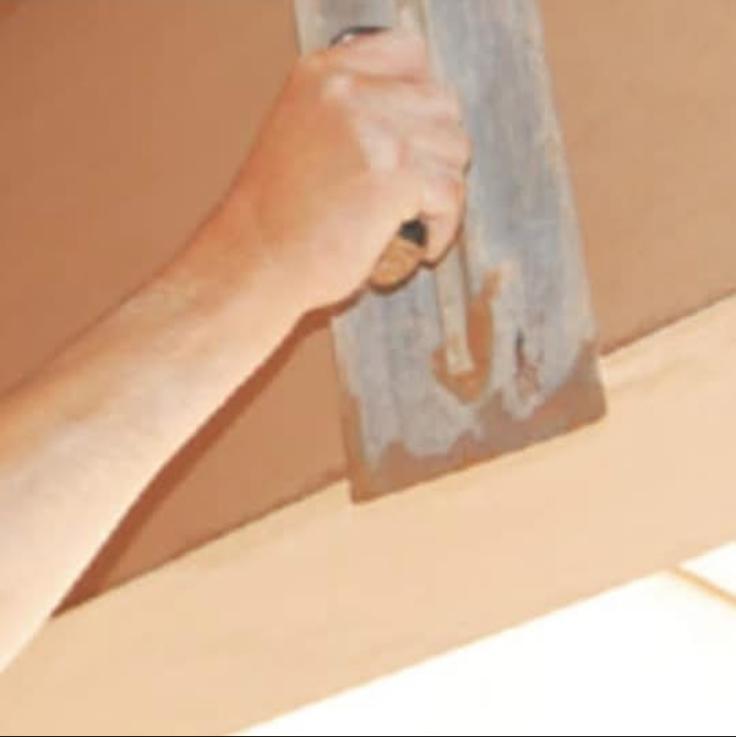 Close-up of a plasterer hand-floating fresh pink plaster with a wooden float