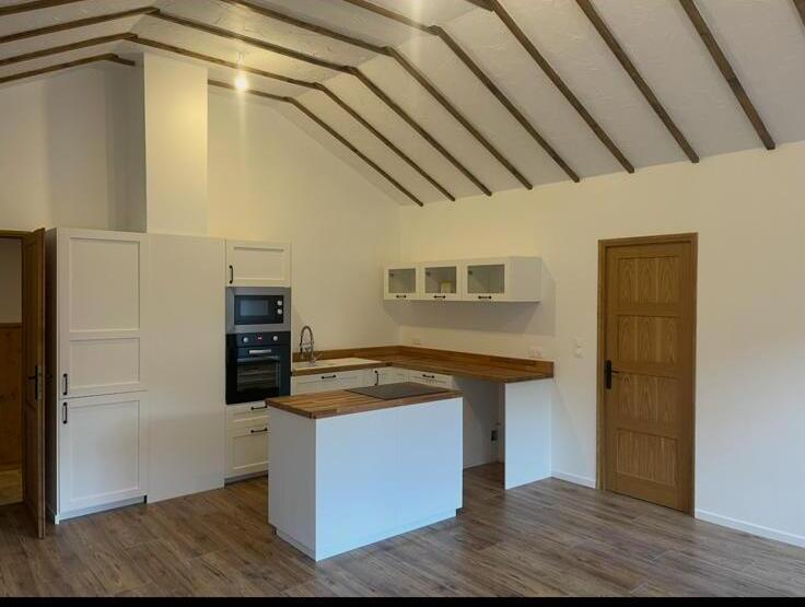 Finished open-plan kitchen with smooth plastered walls and white-painted ceiling between dark timber beams
